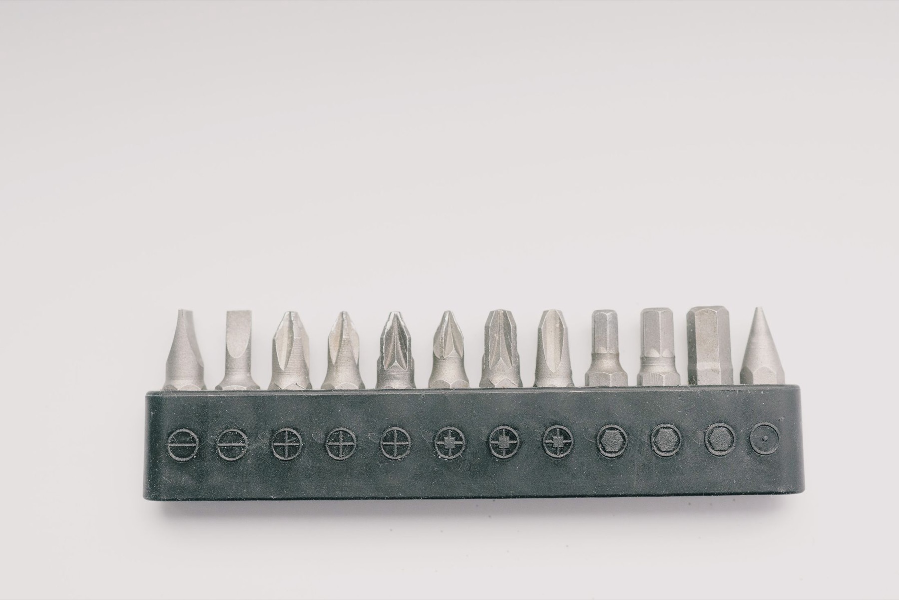A row of screwdriver bits laid out in their holder on a pale surface